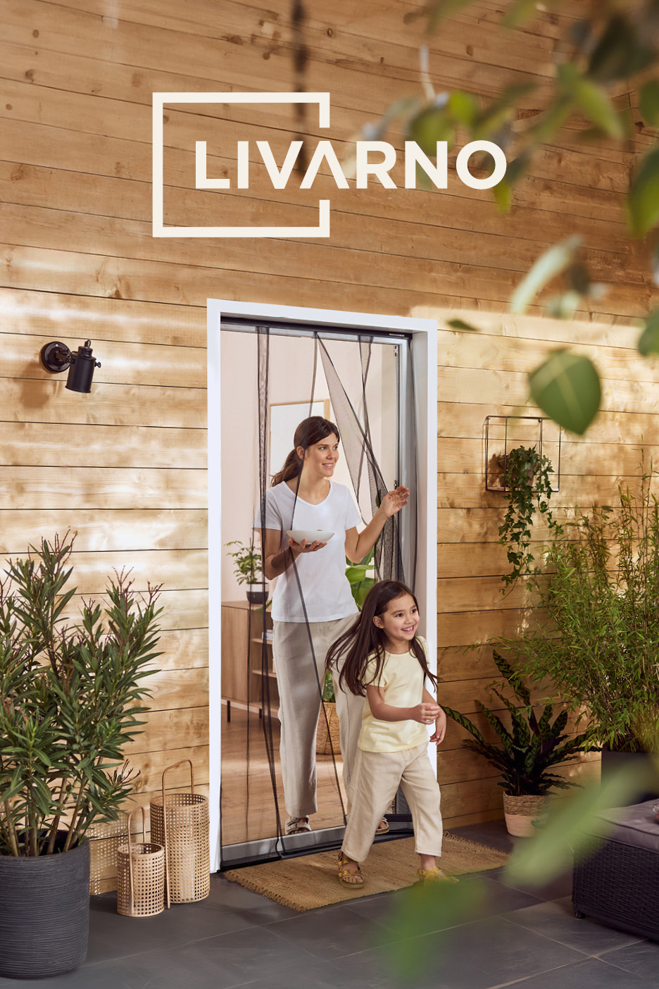 Una donna e una bambina escono da una porta con una zanzariera magnetica, circondate da piante e un rivestimento in legno.