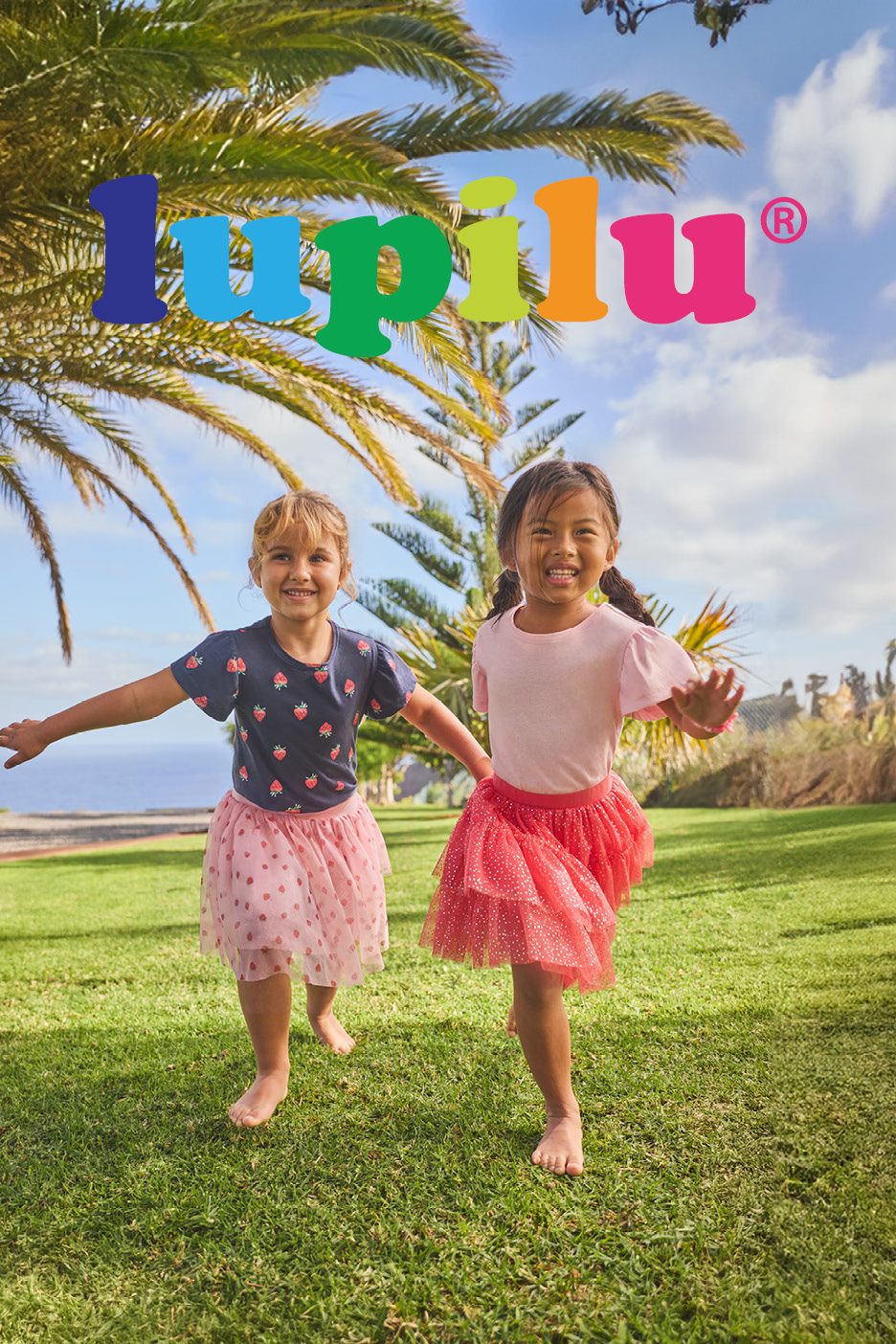 Due bambine in gonne di tulle e magliette con fragole, giocano sull'erba.