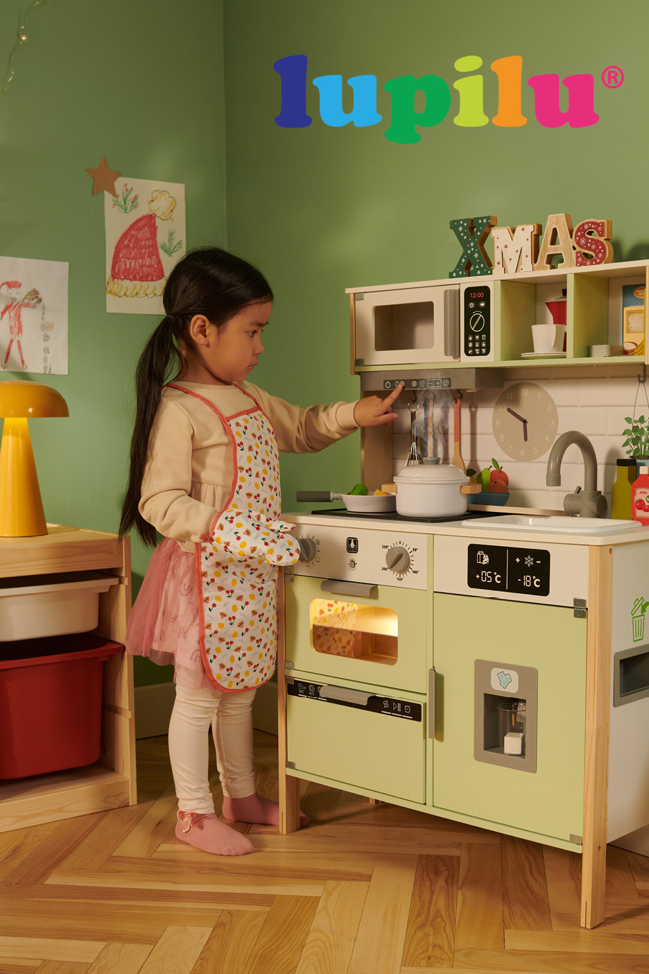 Bambina che gioca con una cucina giocattolo in legno accessoriata.