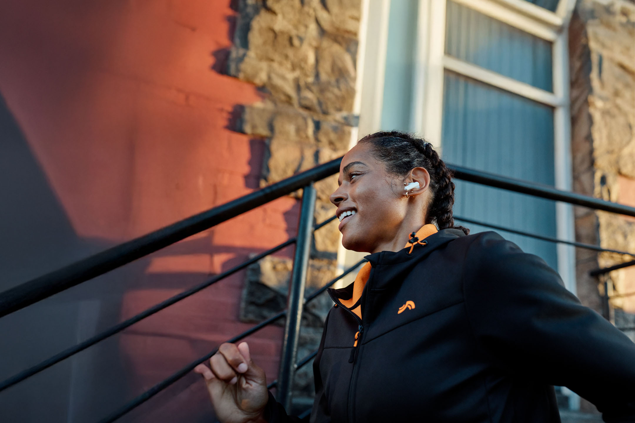 Donna che fa jogging con auricolari, indossa una giacca.